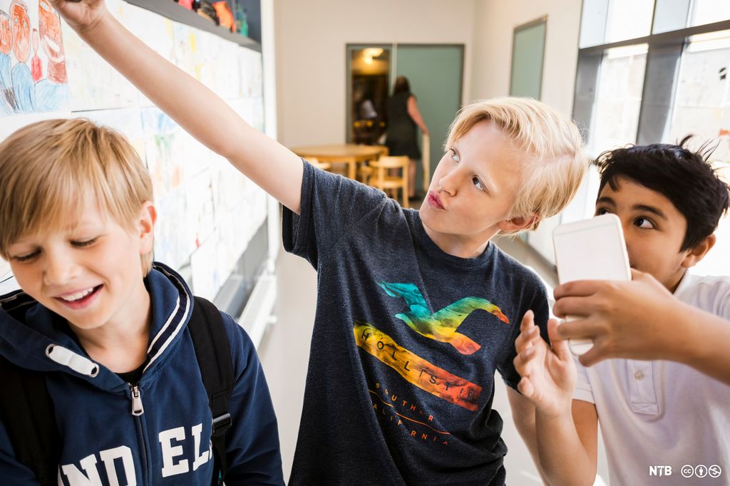 Tre unge gutter tar selfie på skolen. Foto. 