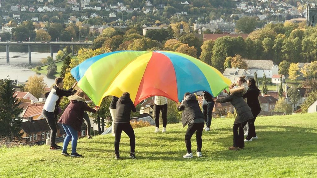 Ungdommer står i sirkel og holder oppe et fargerikt seil.