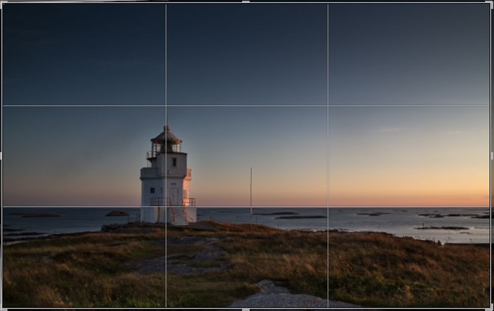 Fyrlykt med hav og horisont. Bildeflaten er delt i tre vertikalt og horisontalt. Fotografi.