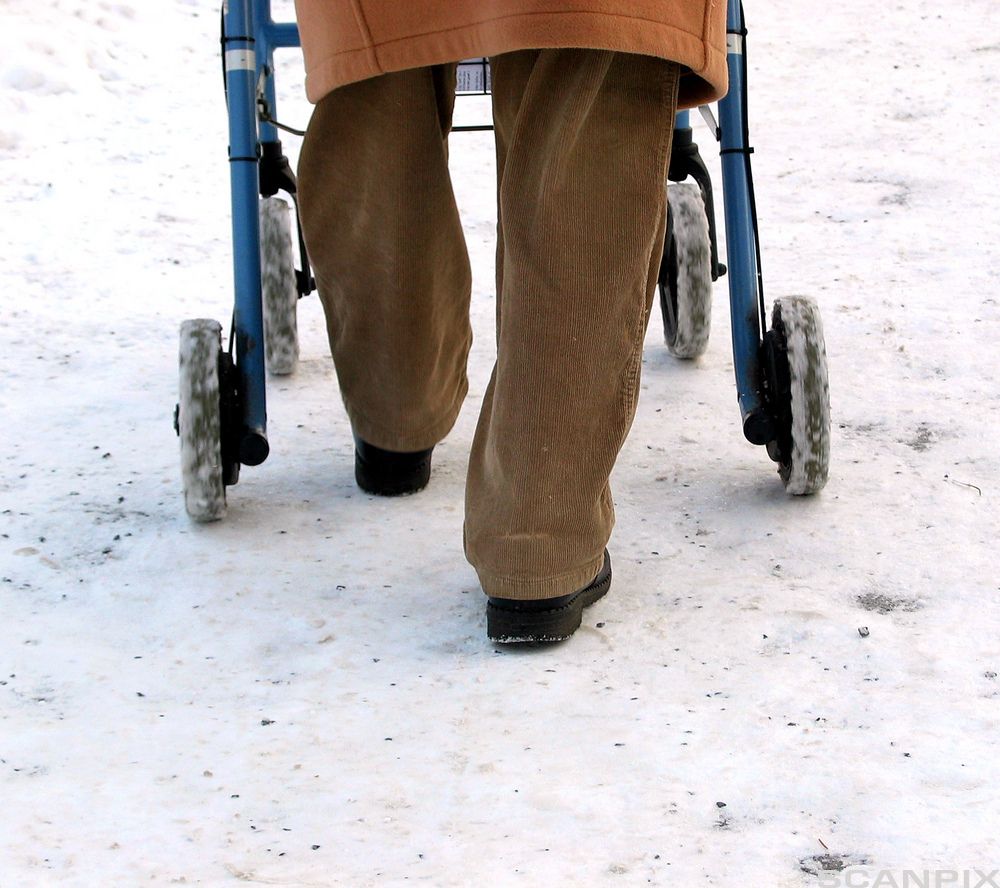 Eldre mann med rullator på glatt vinterføre. Foto.
