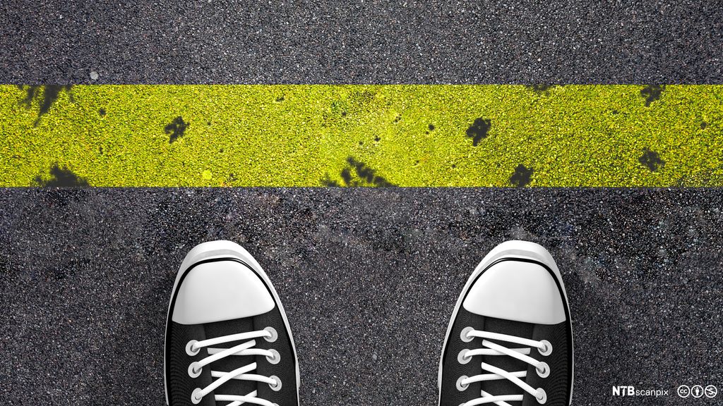 En person med joggesko står foran en gul strek som er malt på bakken. Foto.