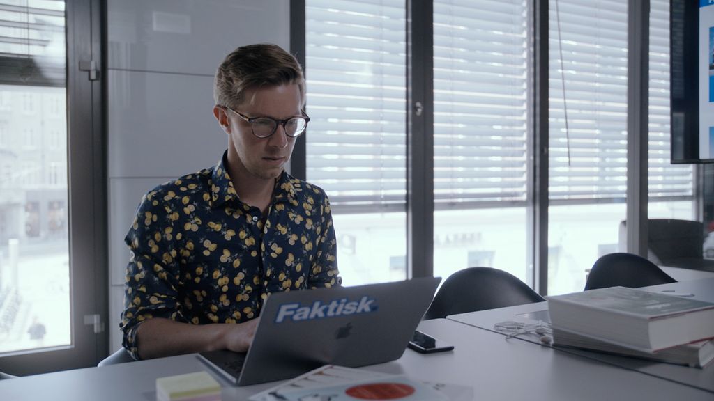 En mann sitter ved et bord og jobber på en datamaksin. Foto.