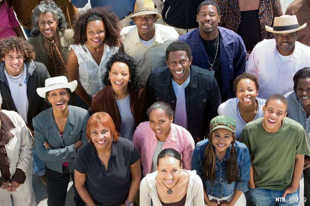A group picture of several African Americans, taken from above. They are looking up at the camera, smiling. Photo.
