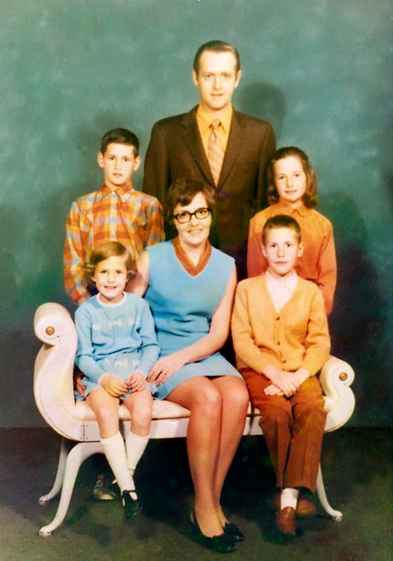 Familieportrett fra ca. 1970. Familien består av mor, far og fire barn, to gutter og to jenter. Den minste jenta, mora og en av guttene sitter foran på en benk. Den andre gutten, faren og den eldste av jentene står bak benken. Foto.