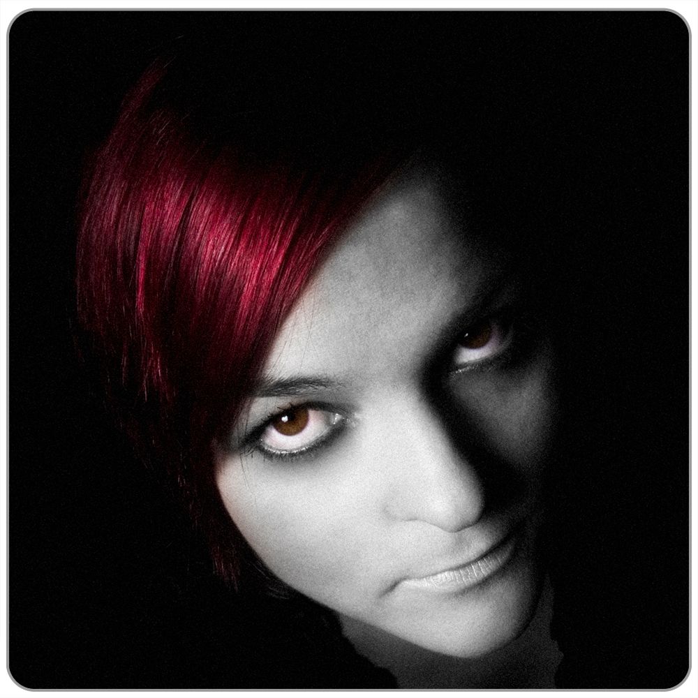 Portrett av jente med rødt hår og mørk bakgrunn. Foto.