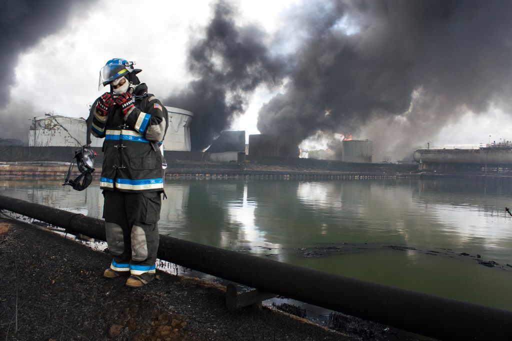 Brannbetjent foran en stor brann i et industrianlegg. Foto.