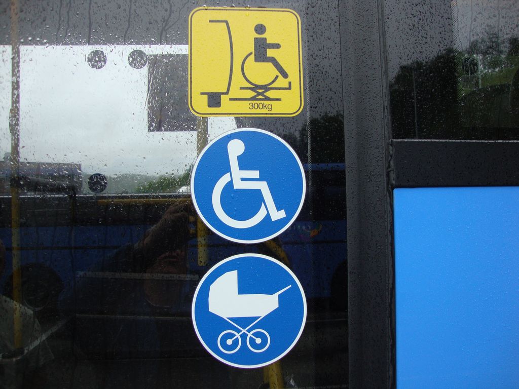 Symboler med rullestol og barnevogn på døra til en buss. Foto.