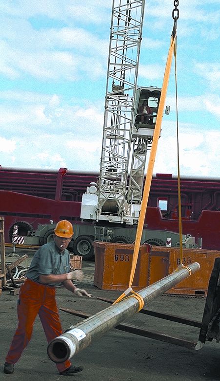 Mann løfter rør ved hjelp av snaring. Foto.