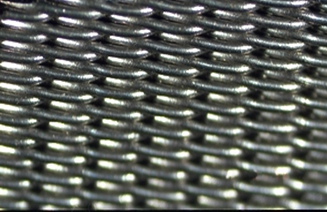 Filterduk. Ståltråd som er vevd over tverrgående ståltråder danner et rutenett. Hullene mellom trådene er åpninger som slipper fast stoff, væske eller gass gjennom filteret. Foto.