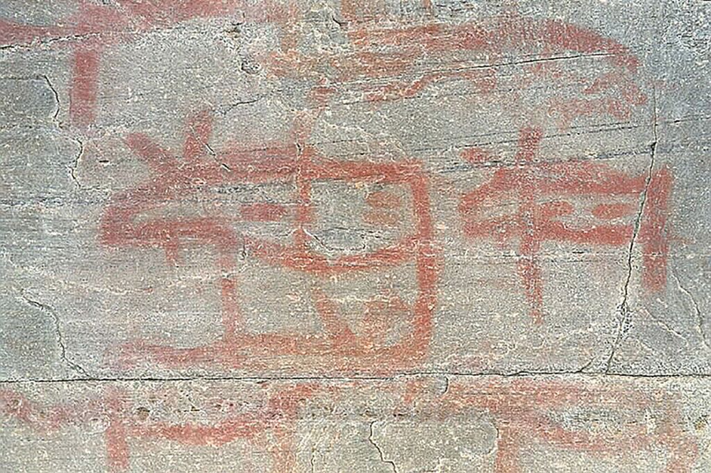 Røde figurer malt på berg. Foto