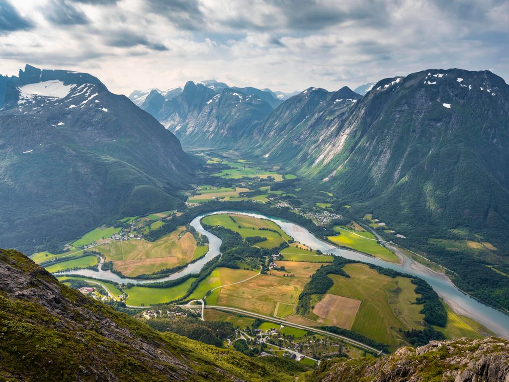 Oversiktsbilde over fjellandskap med åkre, elver og veier i bunnen. Foto.