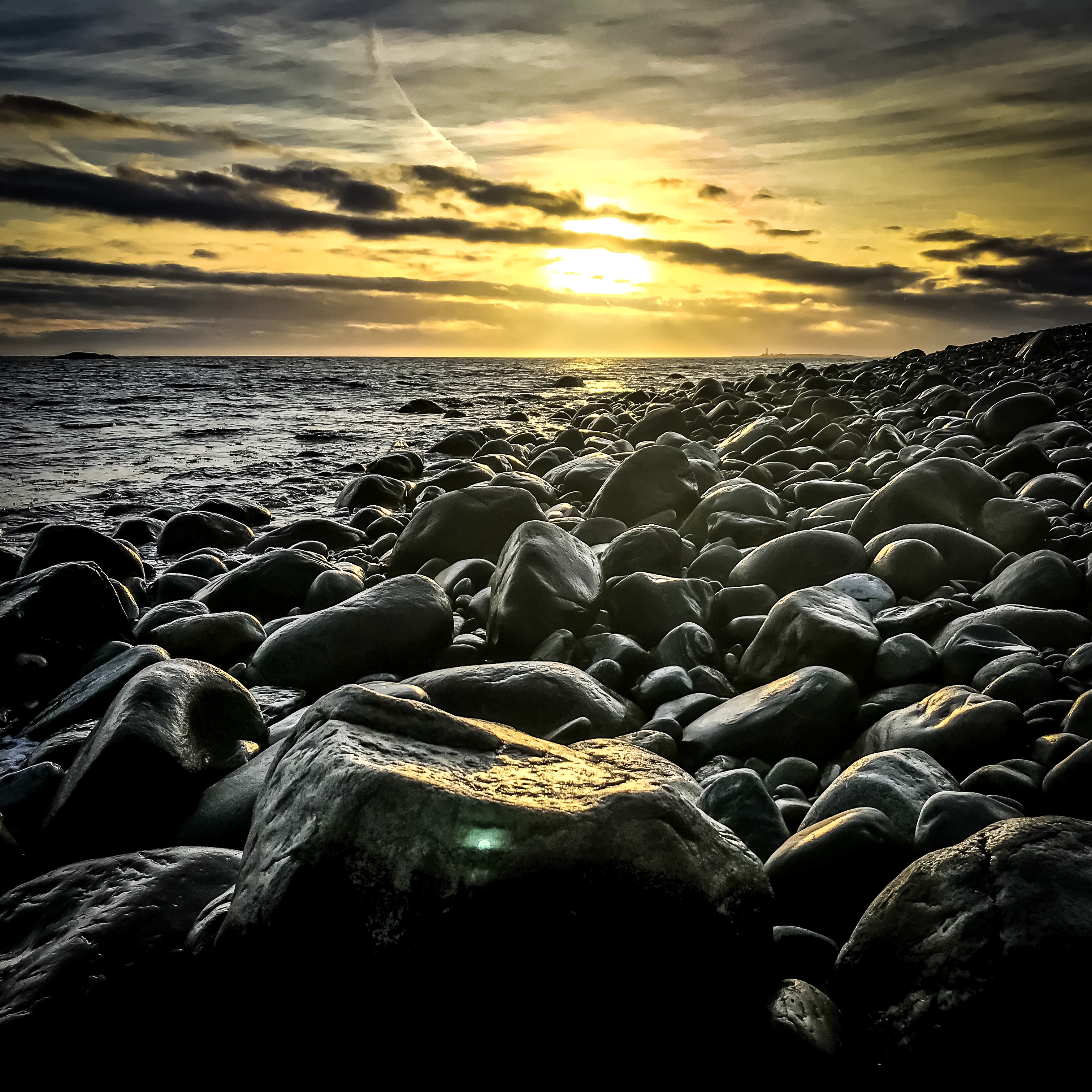 Rullesteinstrand i solnedgang. Foto.