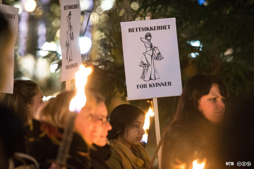 Fleire kvinner står med faklar og ein plakat der det står "Rettssikerhet for kvinner". Foto.