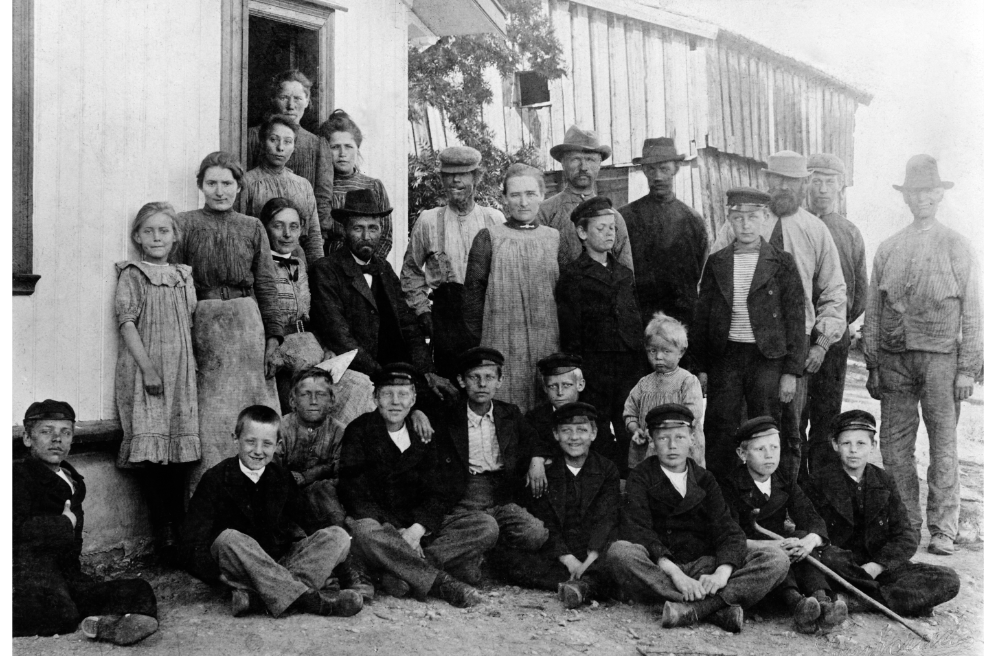Gruppe bestående av rundt 25 voksne og barn på gården Stor-Stav i Ringsaker i Hedmark i cirka 1903. Både tjenestefolk og gårdeiere. Foto.