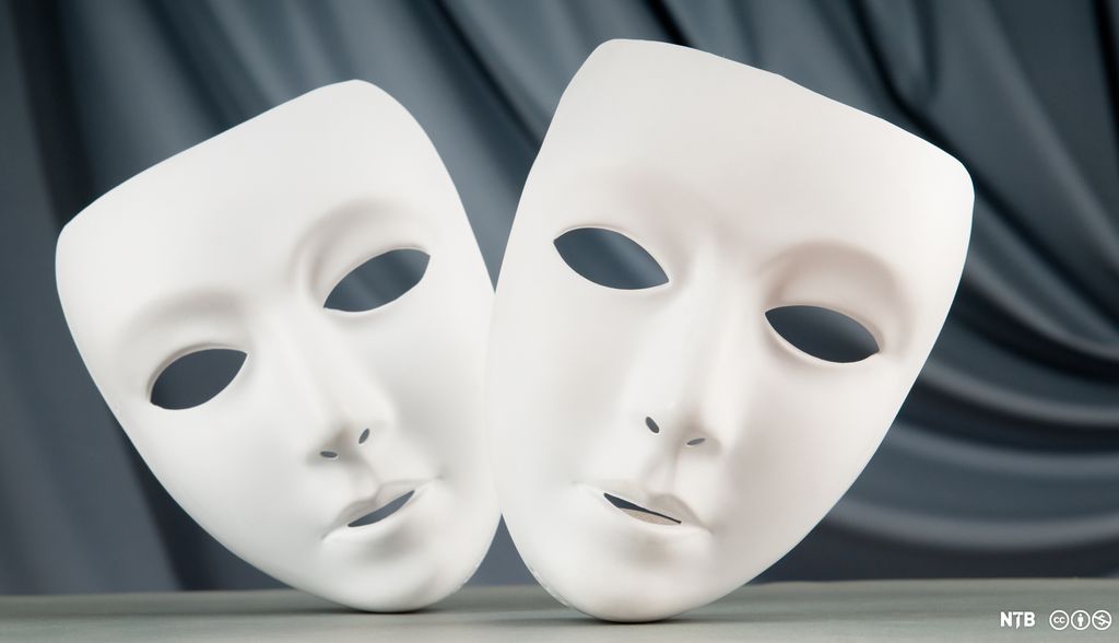 Theatre masks, two white masks with no expression, against a black background. Photo.