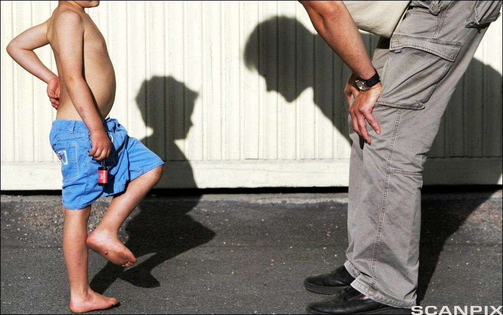 Far bøyer seg over og ser ned på sønnen. Foto.