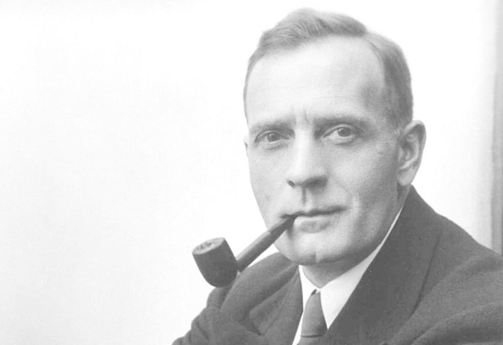 Portrett av mann i dress. Han røyker pipe. Svart-hvitt-foto.