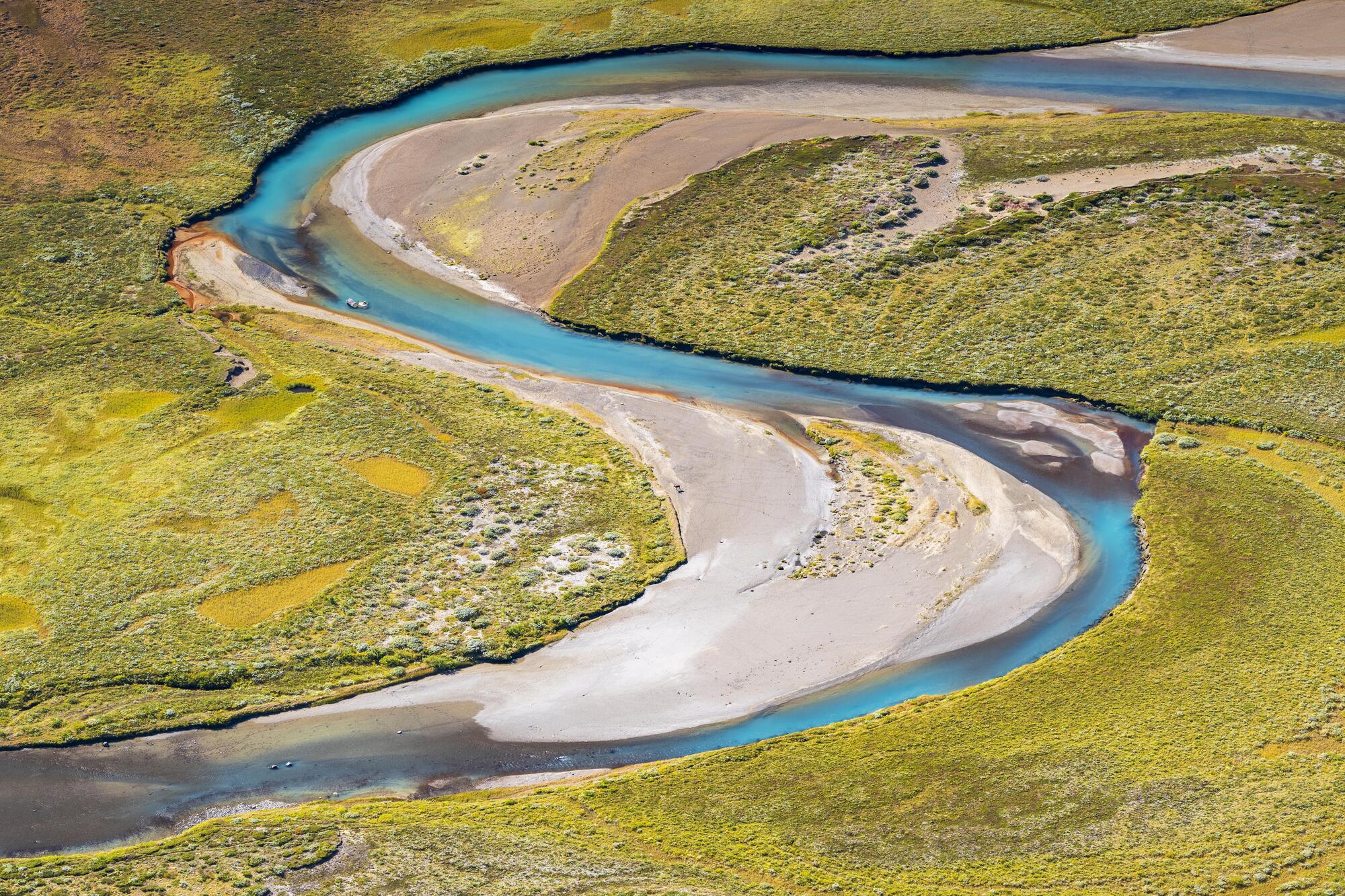 Elv svingar seg nedover i eit landskap. Sandbankar er avsette i innersvingane. Foto.