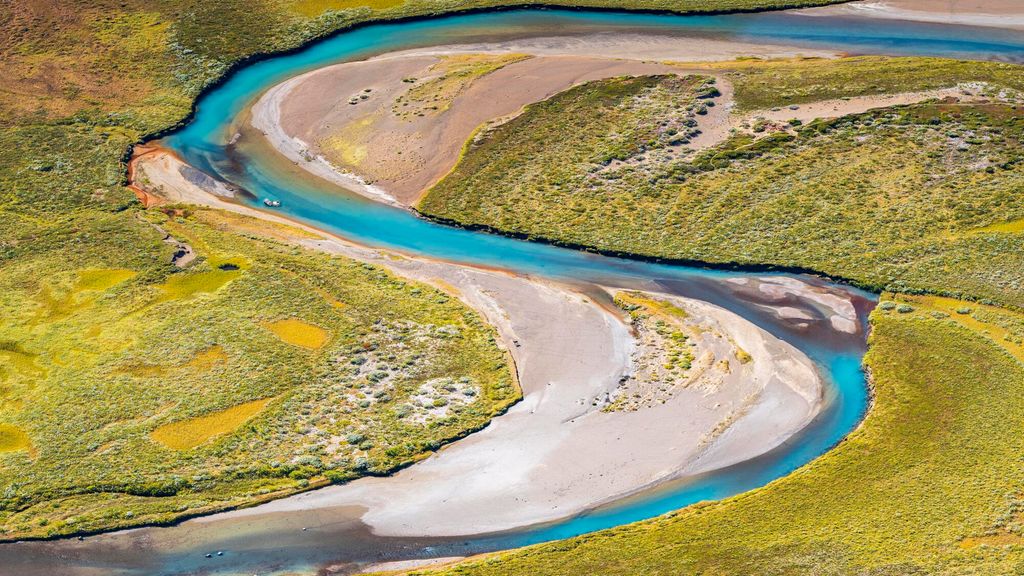 Elv svingar seg nedover i eit landskap. Sandbankar er avsette i innersvingane. Foto.
