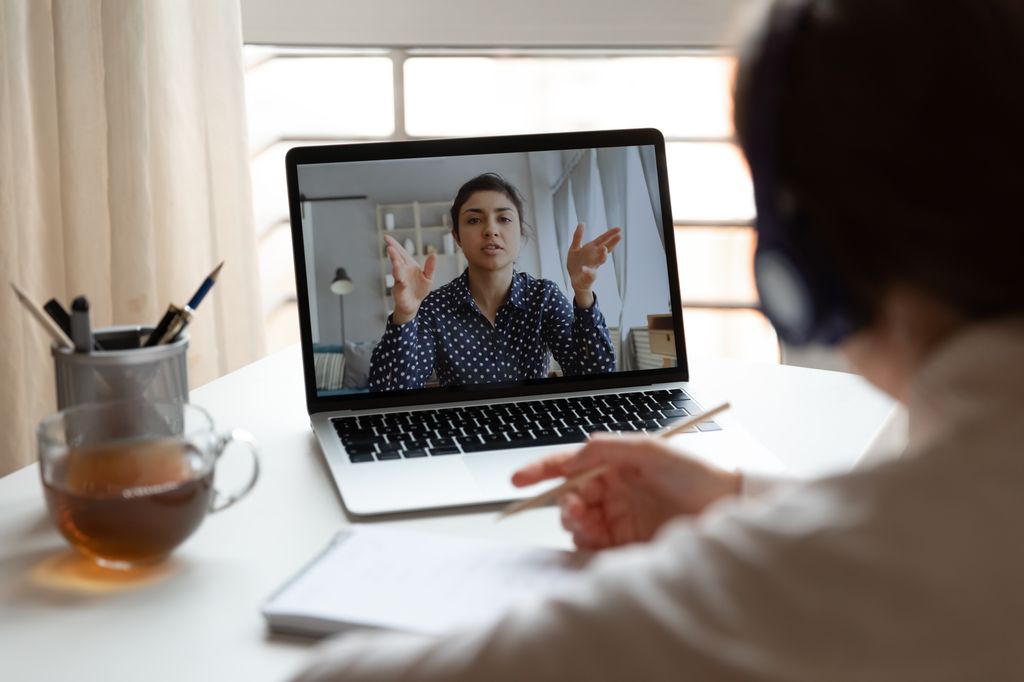 En mann sit framfor laptopen sin og har eit digitalt møte med ei kvinne. Foto.