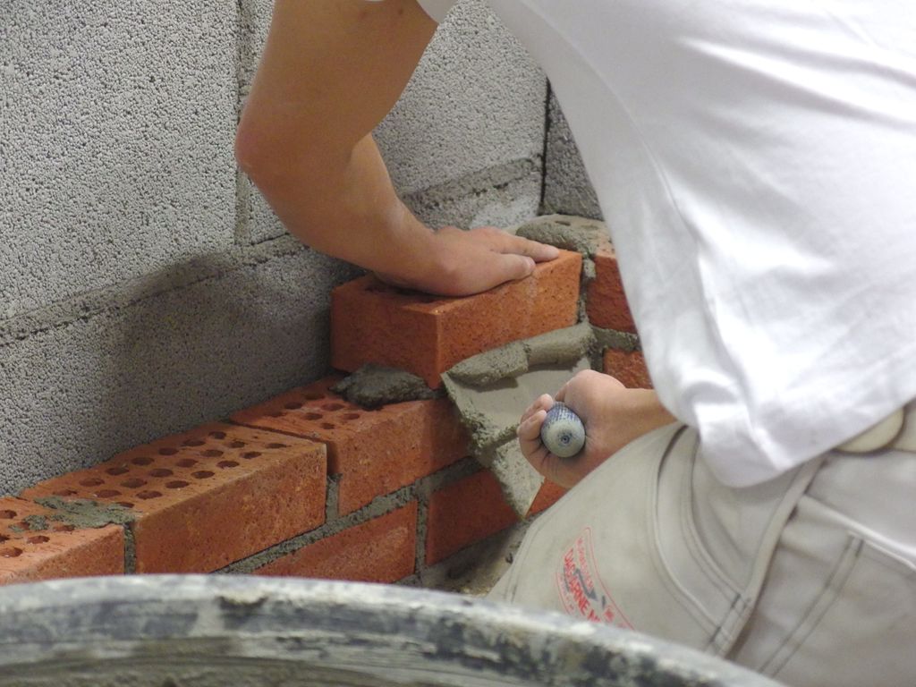 Ein murar murar teglstein med mørtel og murskei. Foto.