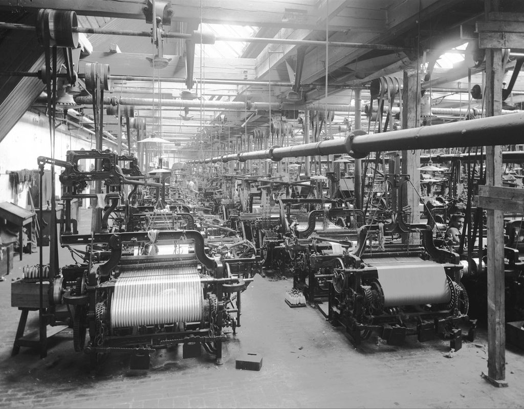 En stor fabrikkhall med ulike spinnemaskiner. Foto fra Hjula Væveri.