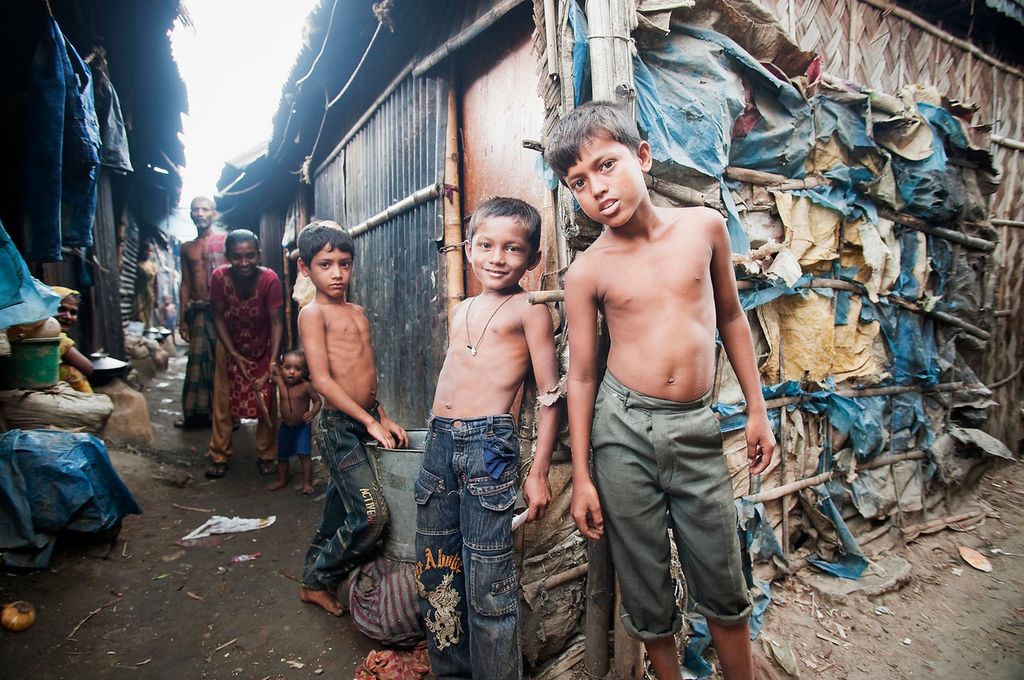 Family on a street corner in Bangladesh slum, woman with small child, man, three boys. Photo.