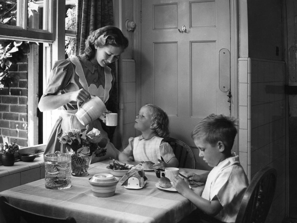 Husmor som serverer frokost til to barn på 1950-tallet. Foto.