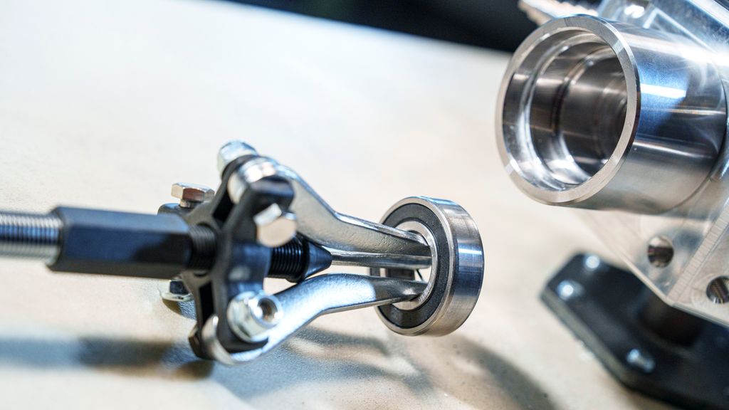 Et sylindrisk verktøy med tre bein festa i et lager. Foto.