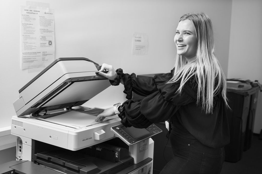 Jente arbeider med å kopiere dokumenter i en kopimaskin. Foto.