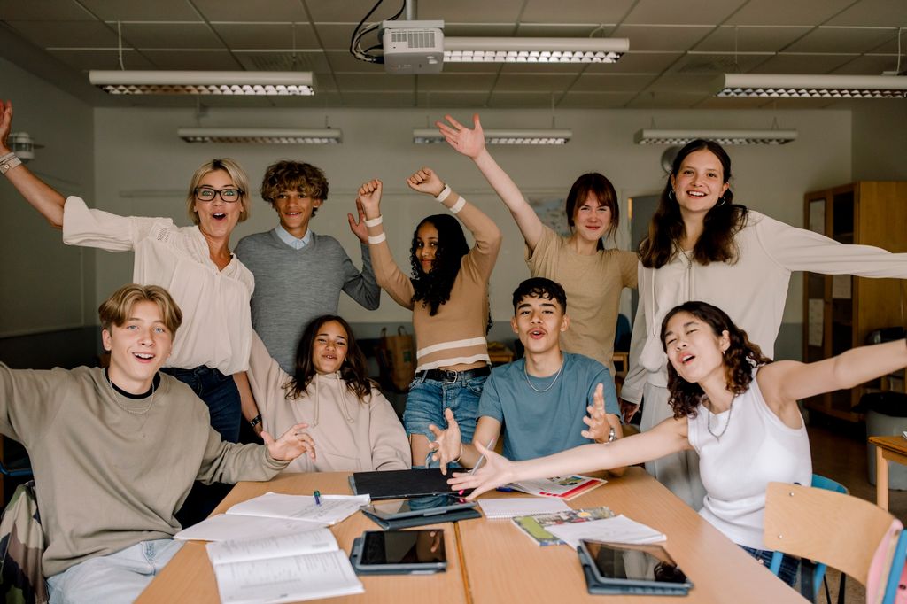 Jublene elever og lærer i klasserom. Foto.