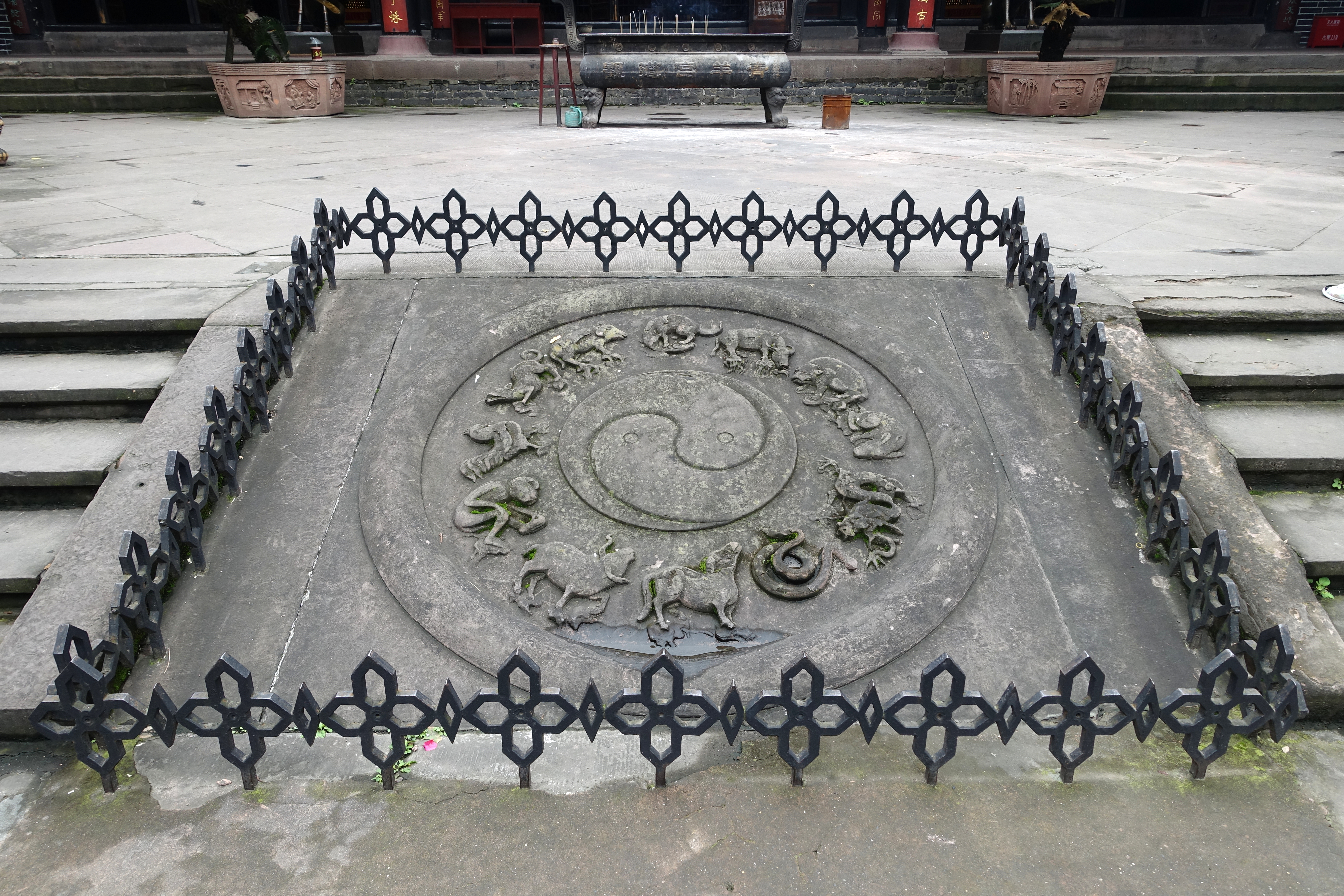 Yin yang-symbol med dyrefigurer rundt støpt i bakken. Foto.