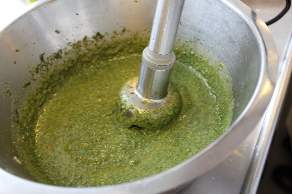 Ein stavmiksar i ein stålbolle med ei sterkt grøn blanding. Foto.