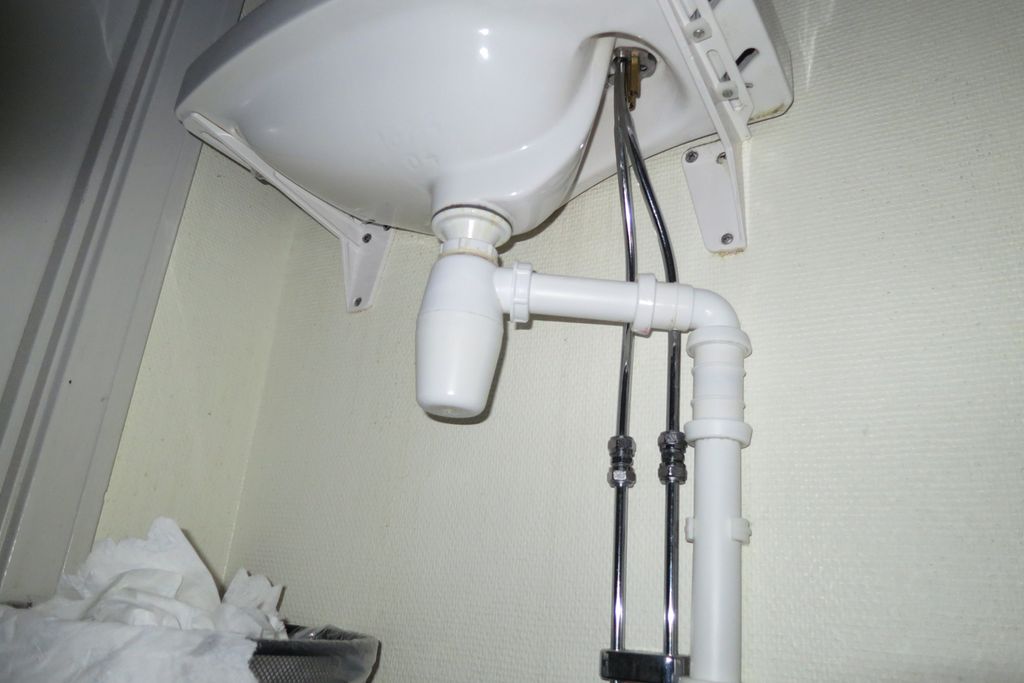 Avløpsrøyr under ein servant. Foto.