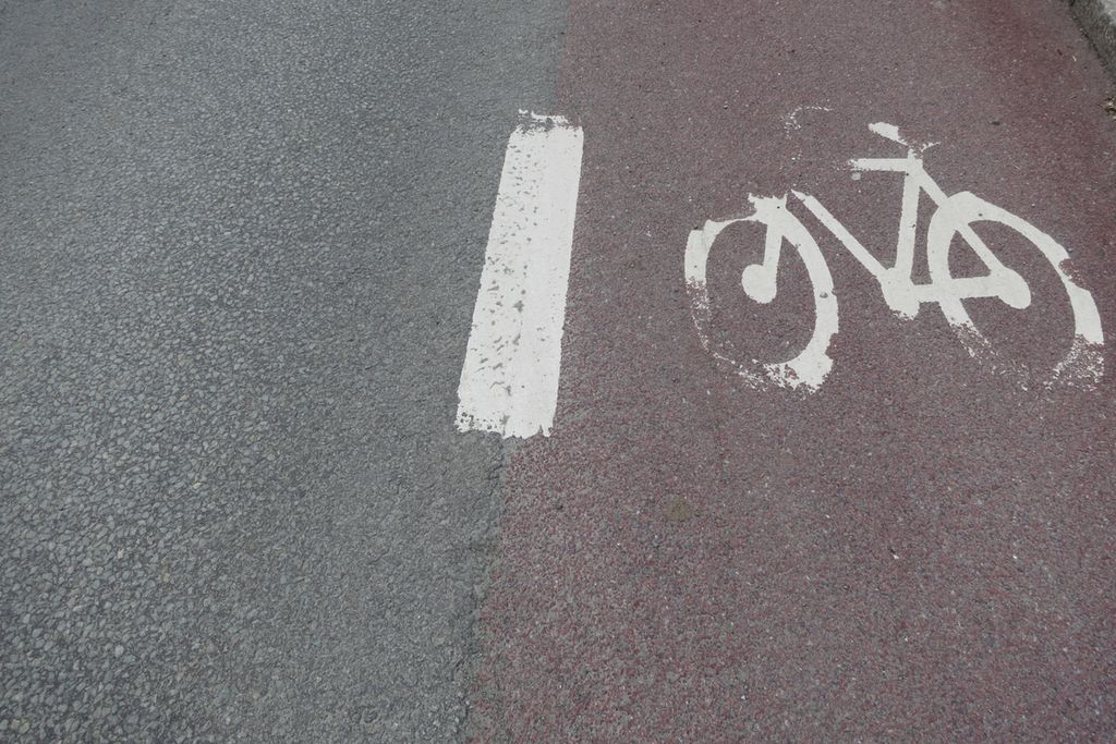 Svart asfalt til venstre og rød asfalt med sykkelfelt til høyre. Foto.