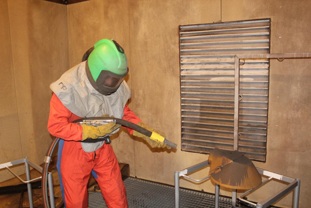 Industrimålar sandblåser gjenstand. Foto.