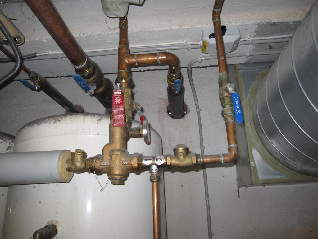 Koparrøyr i eit teknisk rom med varmtvasstank og ventilasjon. Foto.