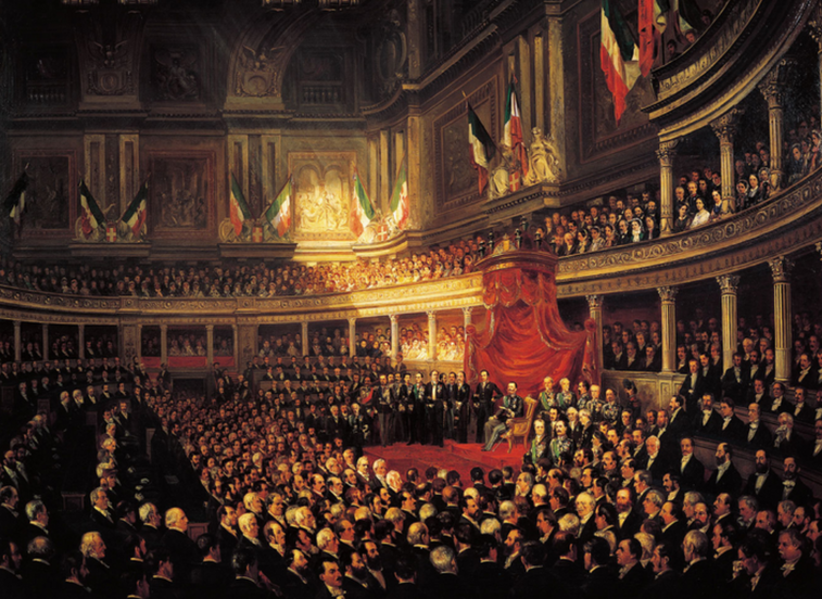 Ei stor forsamling menn nede i ein praktfull sal der ein stor, raud baldakin markerer sentrum over ein opphøgd stol. Tett med menneske sit òg på galleria og balkongane. Der er det òg enkelte kvinner. Italienske flagg heng frå høgda over galleria. Måleri.