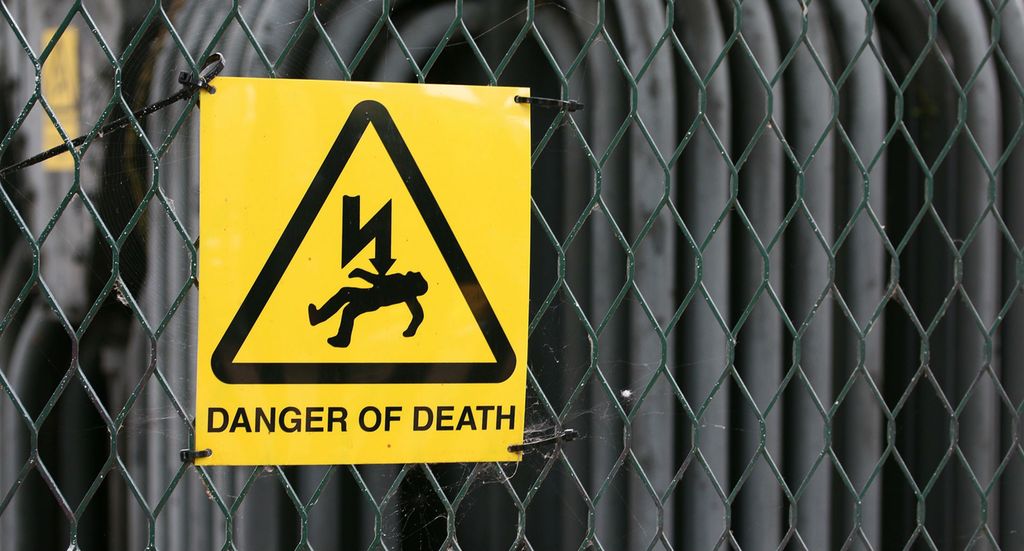 Fareskilt for høyspenning på gjerde. Foto.