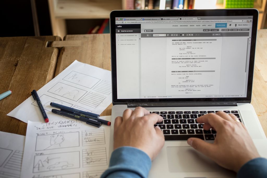 Hender på tastatur skriver manus på laptop. Foto.