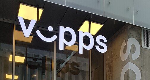 Nærbilde av en kontorbygning. Hvite bokstaver som danner ordet Vipps er montert og lett synlig i front. I-en er formet som et slags smilefjes. Foto.