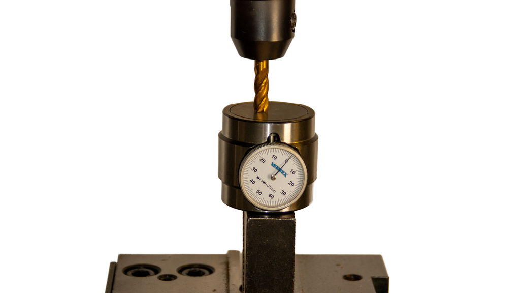 Måleur som står på et arbeidsstykke som er festa i ei maskinstikke. En fres presser mot måleuret, og måleurets viser peker på tallet null. Foto.