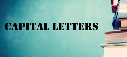 Illustration: The words CAPITAL LETTERS on a blue background. On the right the edge of a pile of books is seen.