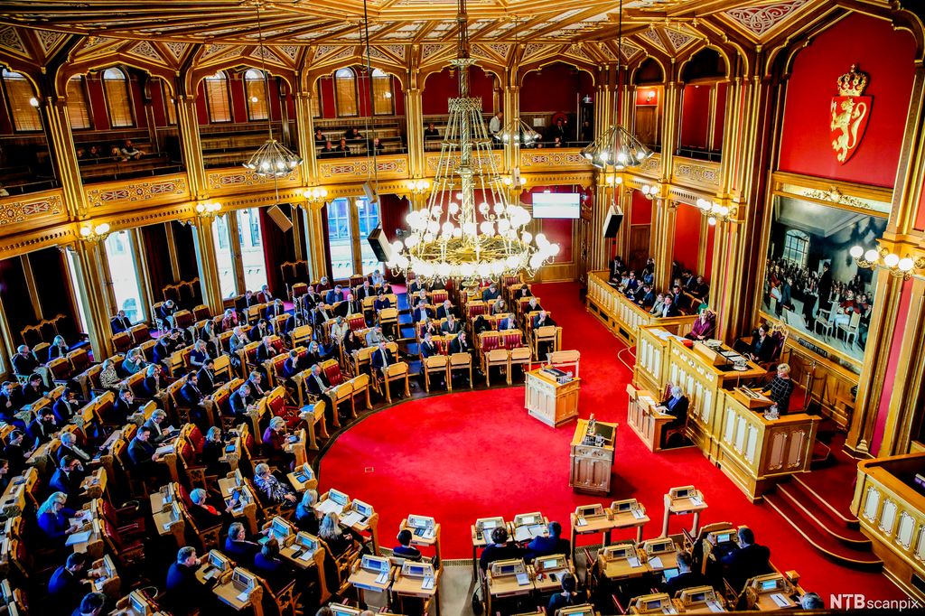 Politikere, president, sekretær, publikum og referent i stortingssalen. Foto.