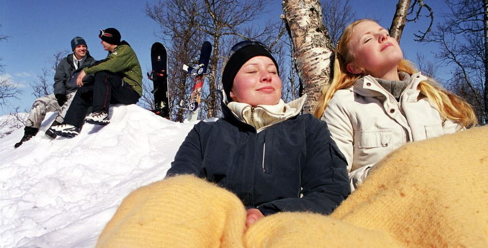 To jenter som soler seg i snøen. Foto.