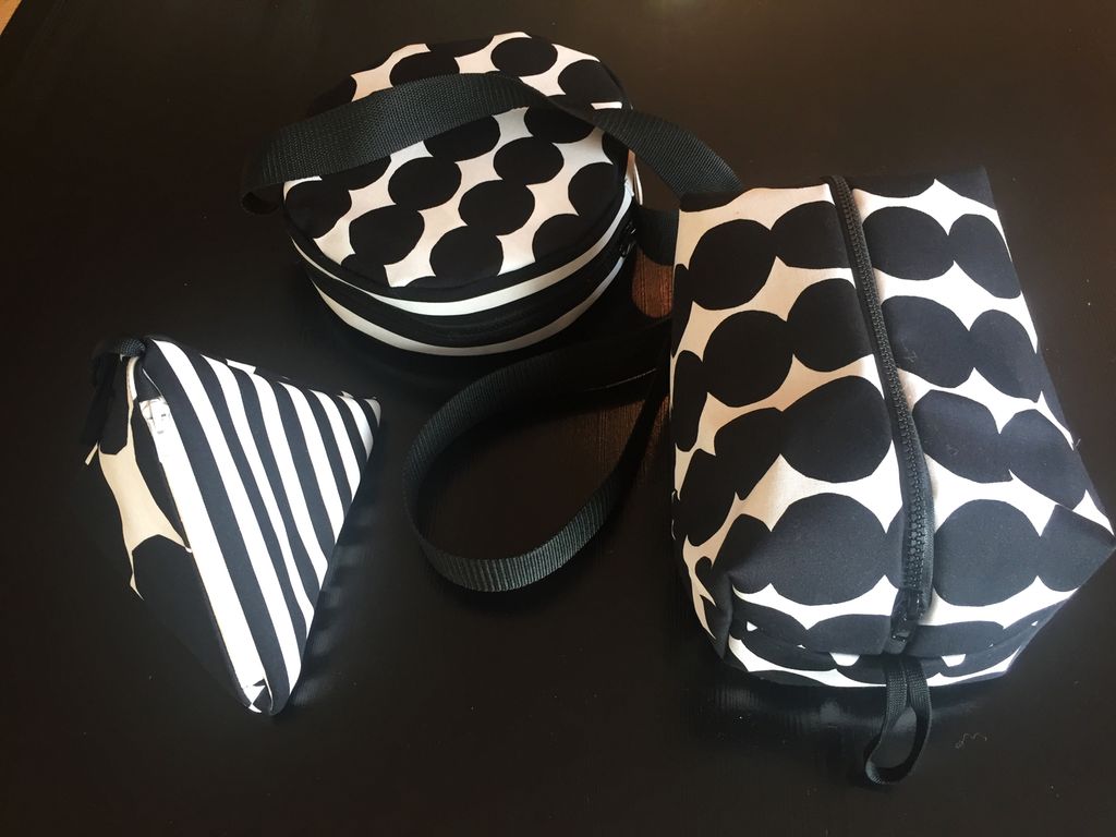 Tre vesker med svart-hvitt-trykk. Til venstre en stripete veske med trekantform. Oppe i midten en sirkelformet veske og til høyre en rektangelformet veske, begge med sorte sirkler på hvit bunn. Foto. 