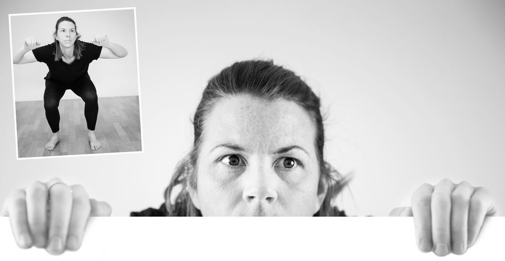 Jente står på huk og kikker over en tenkt kant. Foto.