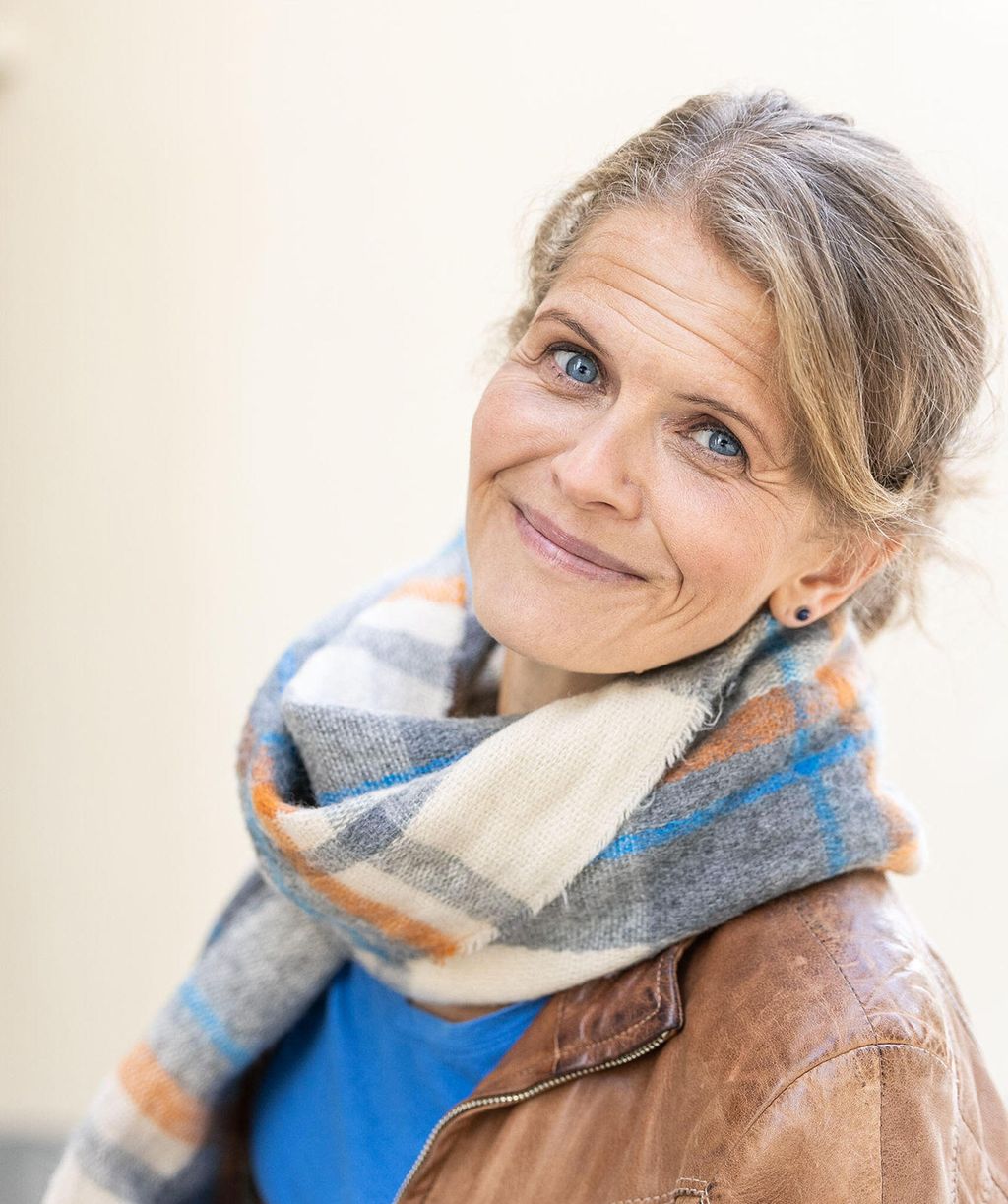 Smilende dame ser inn i kameraet. Foto.