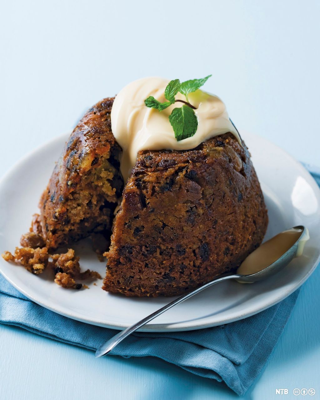 Engelsk Christmas pudding servert på et fat med en vaniljecustard på toppen. Foto.