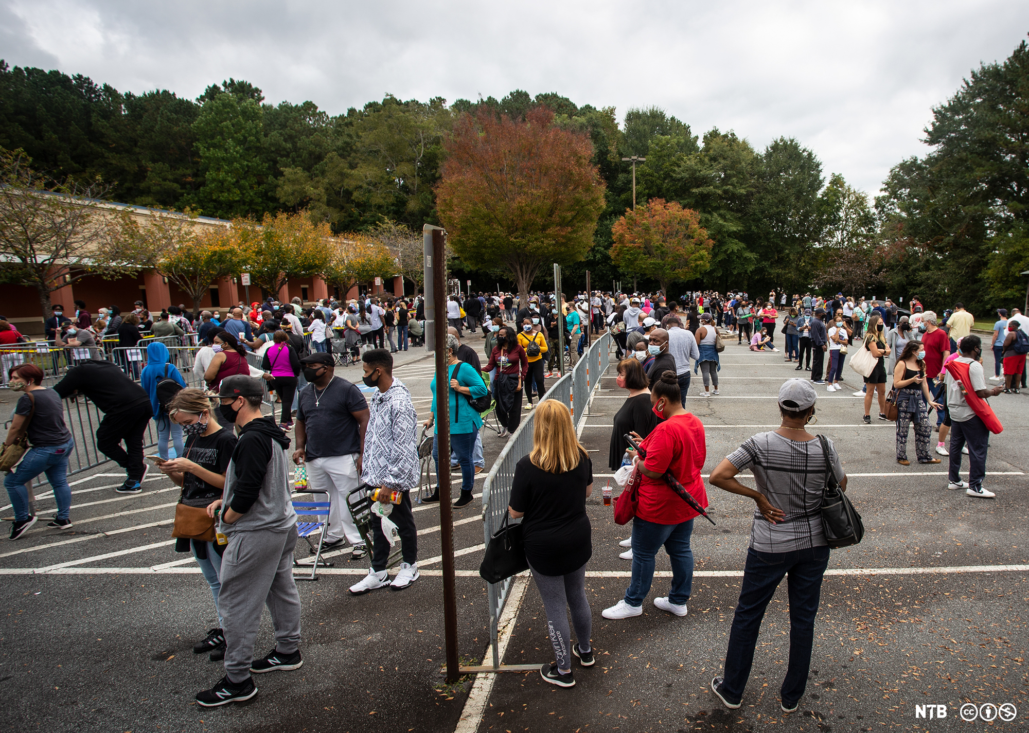 Photo: We see a lot of people standing in a parking lot. 
